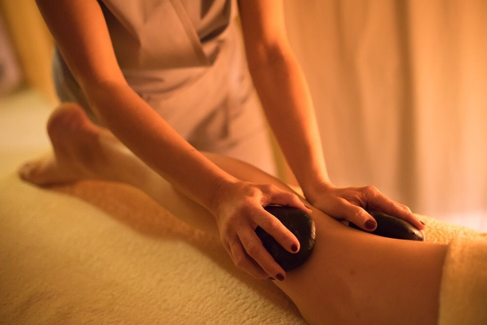 Persona che riceve un massaggio con pietre calde alla gamba in una spa.