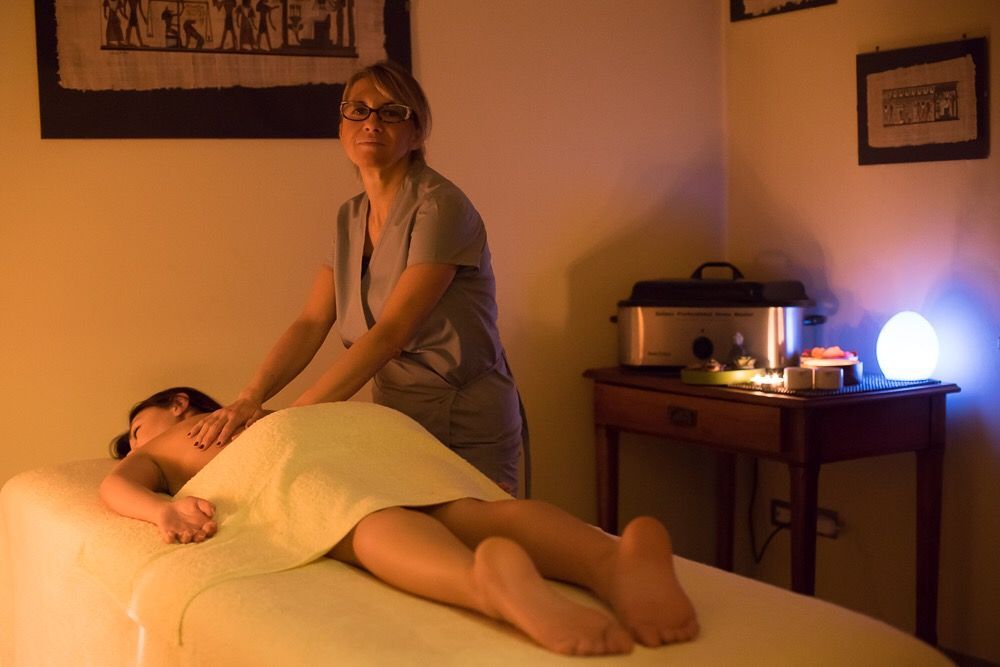 Una donna riceve un massaggio da un'altra donna in una spa scarsamente illuminata.