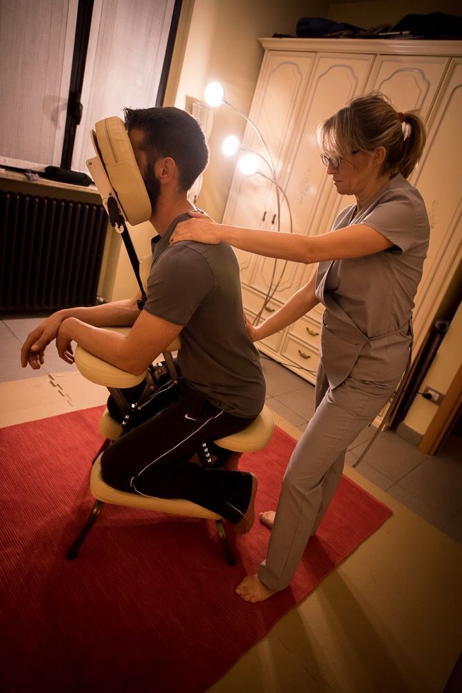 Una persona riceve un massaggio da un'altra persona in una stanza con un tappeto rosso.