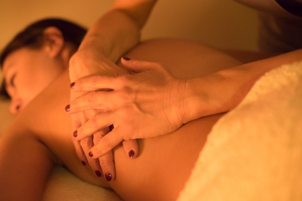 Persona che riceve un massaggio alla schiena, mani del terapista sulla spalla. Luce calda, asciugamano.