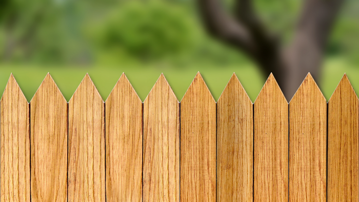 A close up of a wooden fence with a tree in the background.