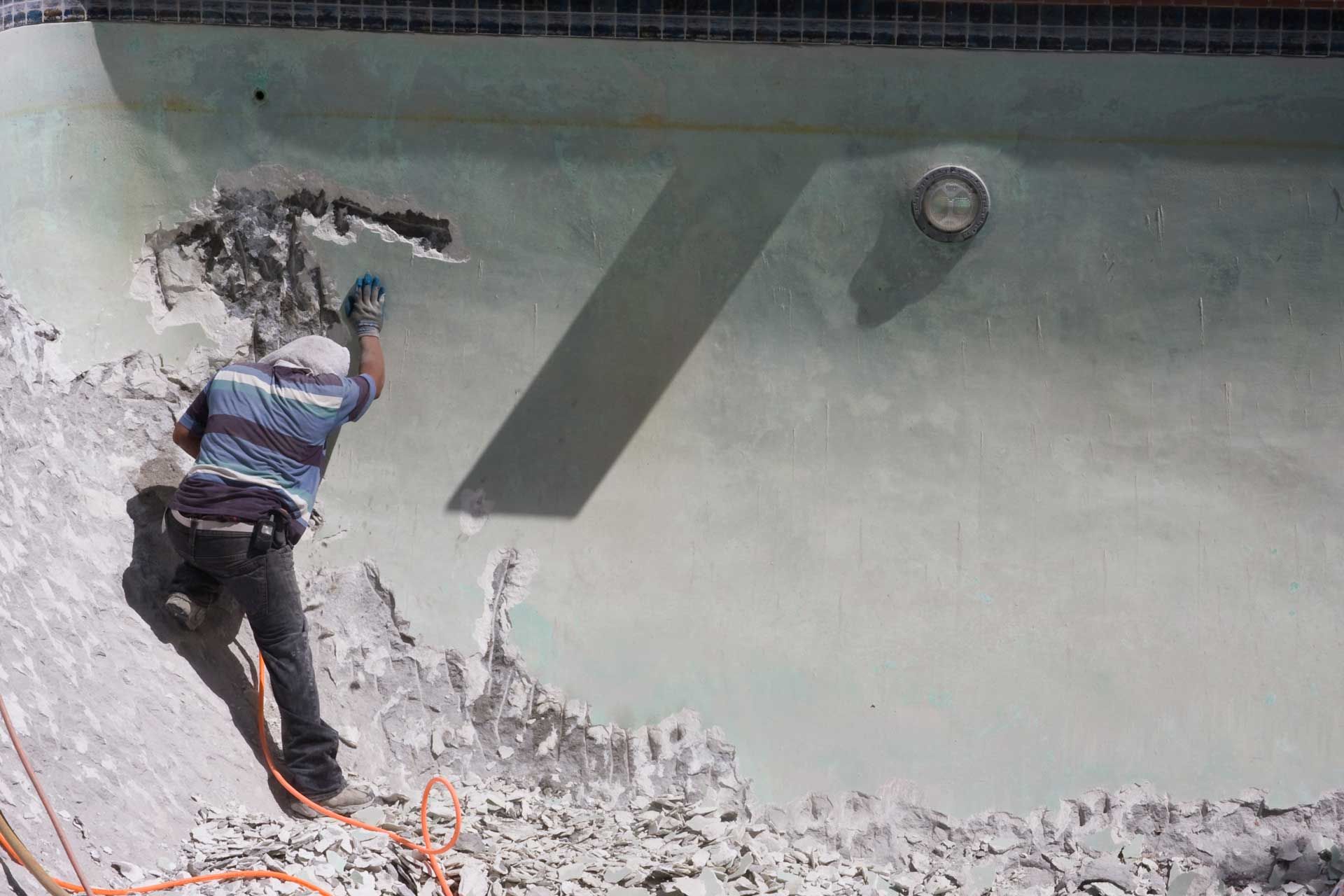 A Man Is Working On The Side Of A Swimming Pool — St. Louis, MO — Aqua Ridge Pool Finishing