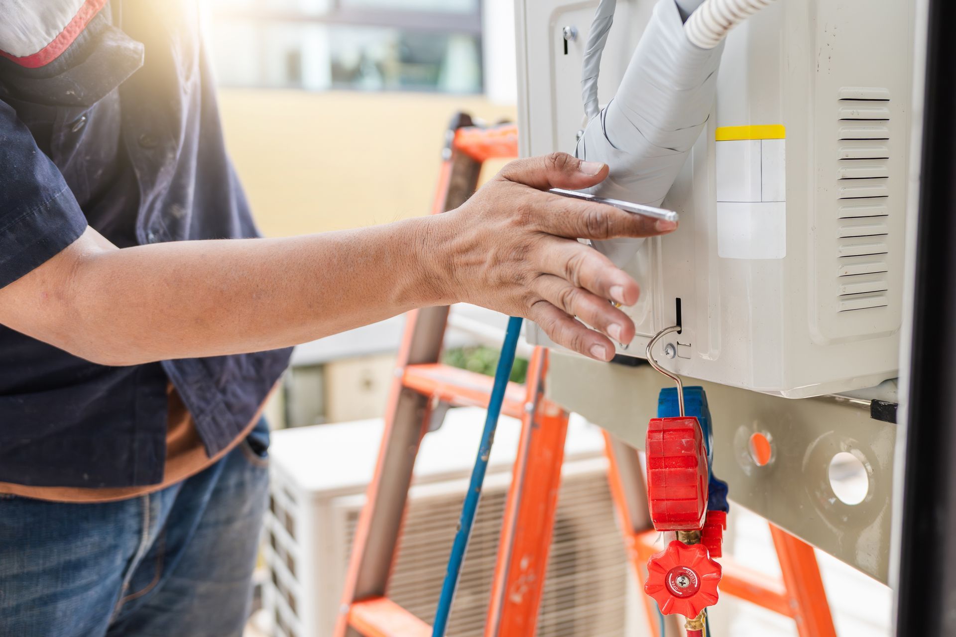 Technician installing or maintaining an air conditioning unit on an outdoor ladder.