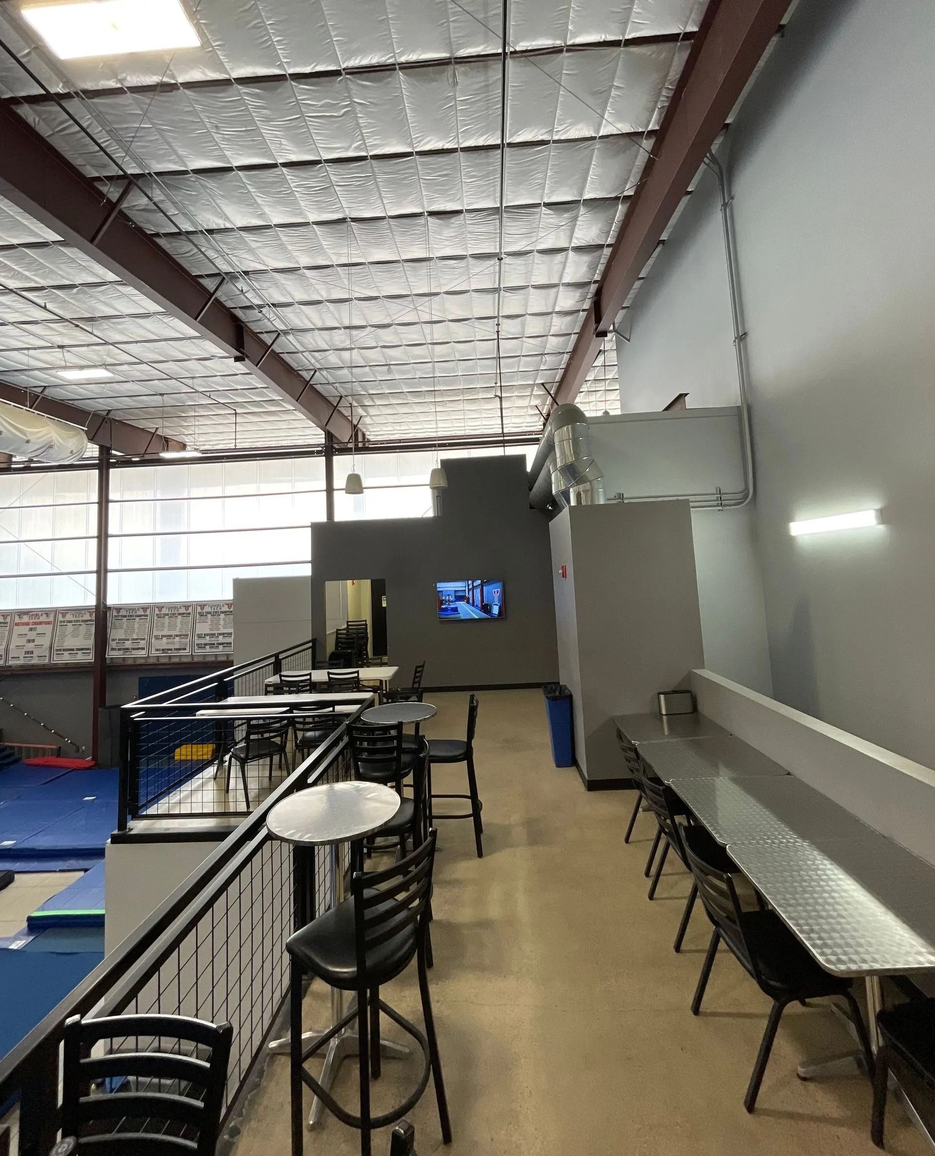 Indoor Area with Tables, Chairs, and Metal Railing Overlooking a Gym Space — Cedar Park, TX — Tech Cheer