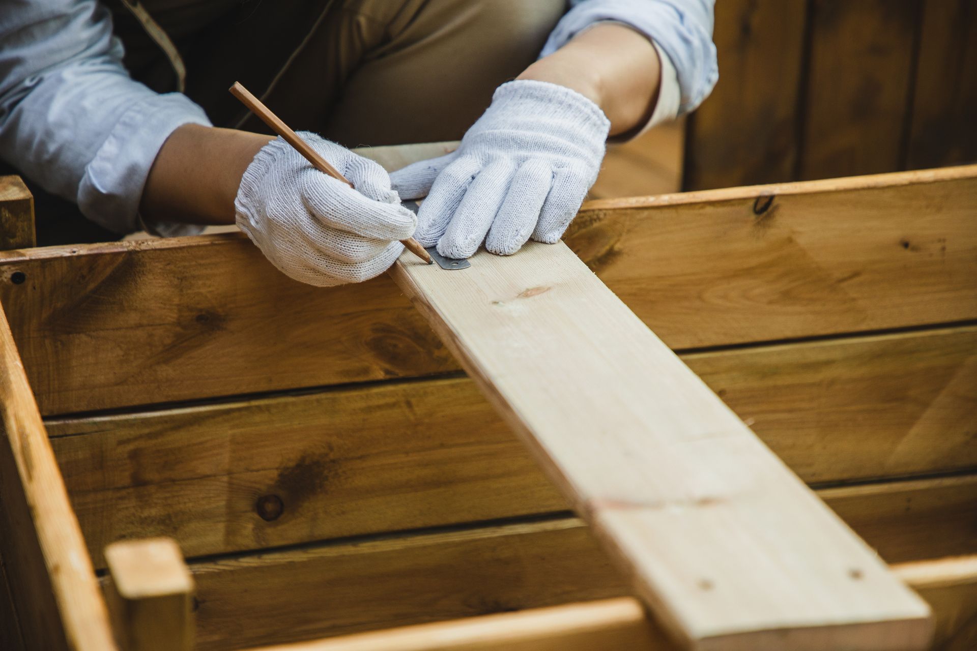 Una persona misura un pezzo di legno con un metro a nastro.