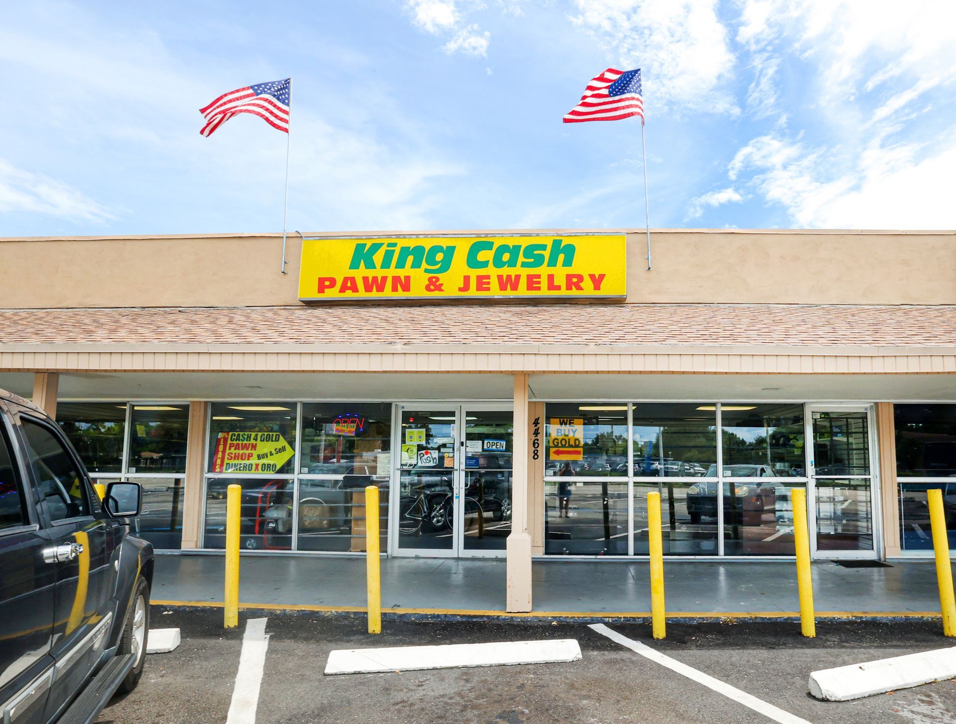 Exterior view of King Cash Pawn & Jewelry on Hallandale Beach blvd. with two American flags on the roof.