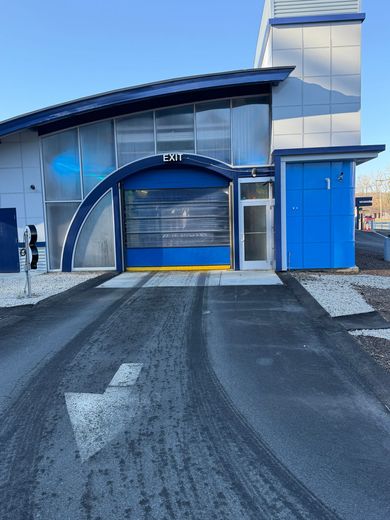 Hand washing a dark gray car with a soapy sponge outdoors.