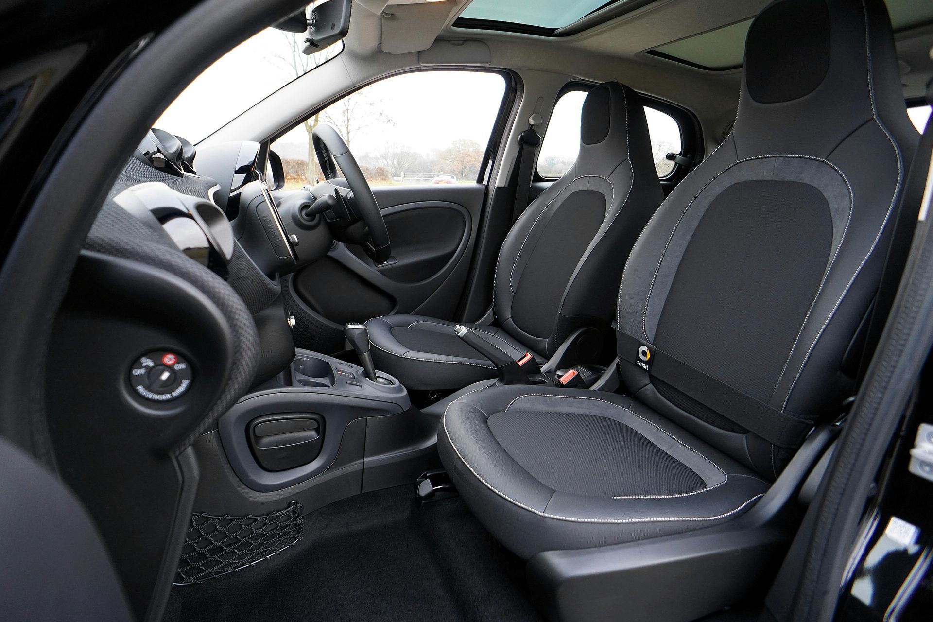 Interior of a black compact car, showcasing the front seats, steering wheel, and dashboard.