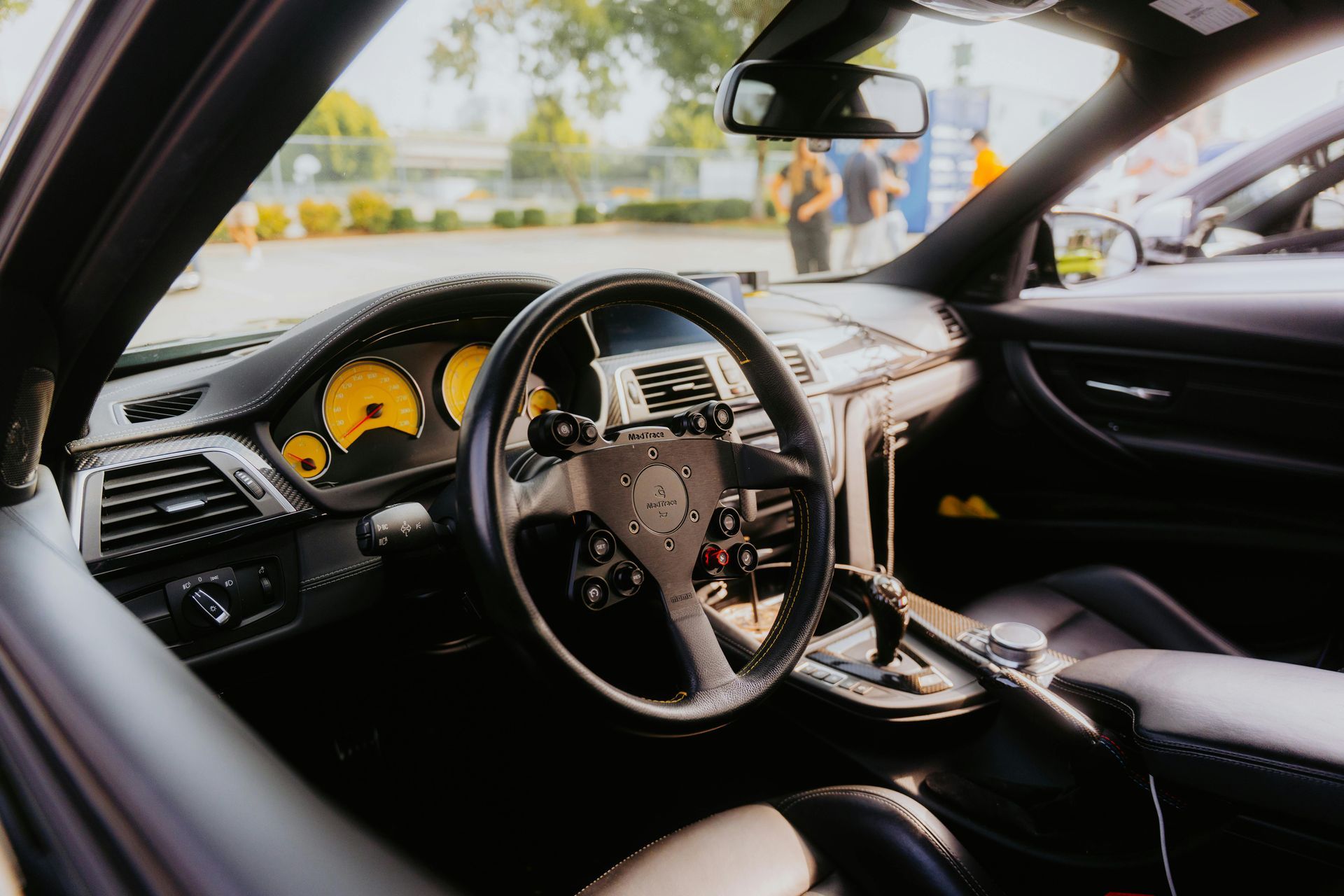 Black car interior with yellow gauge cluster and modified steering wheel.
