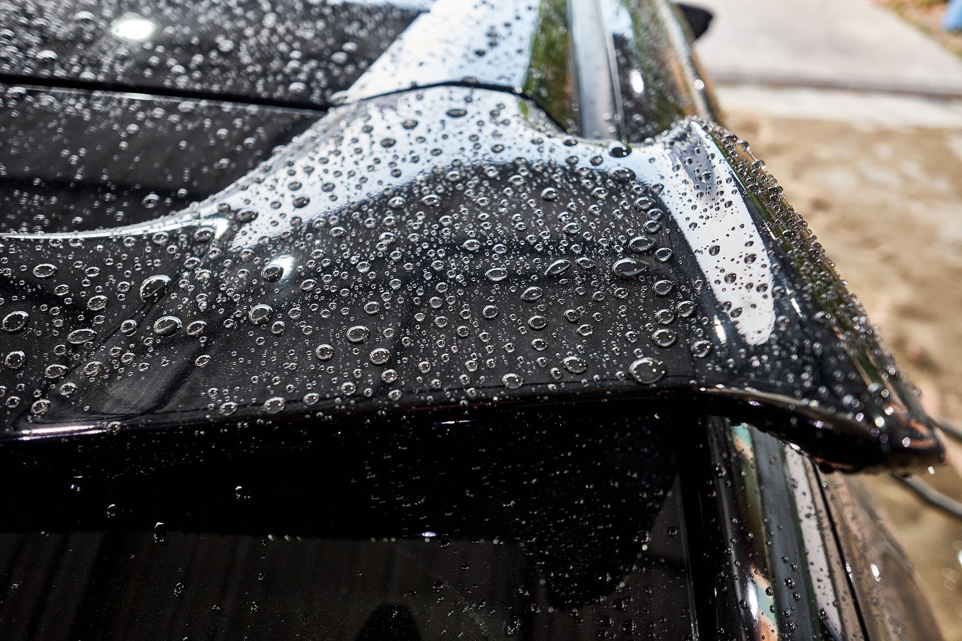 Black car spoiler covered in water droplets.