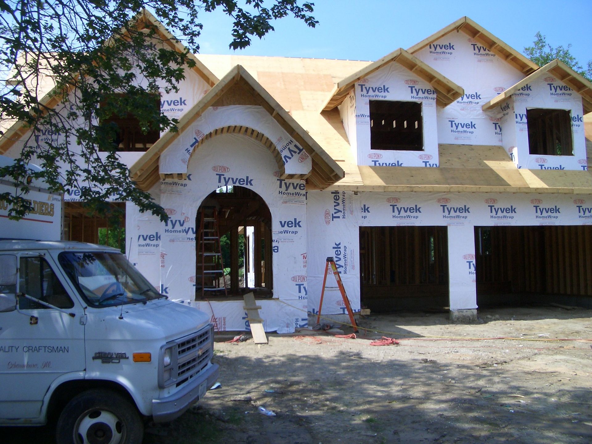 A white van is parked in front of a house under construction