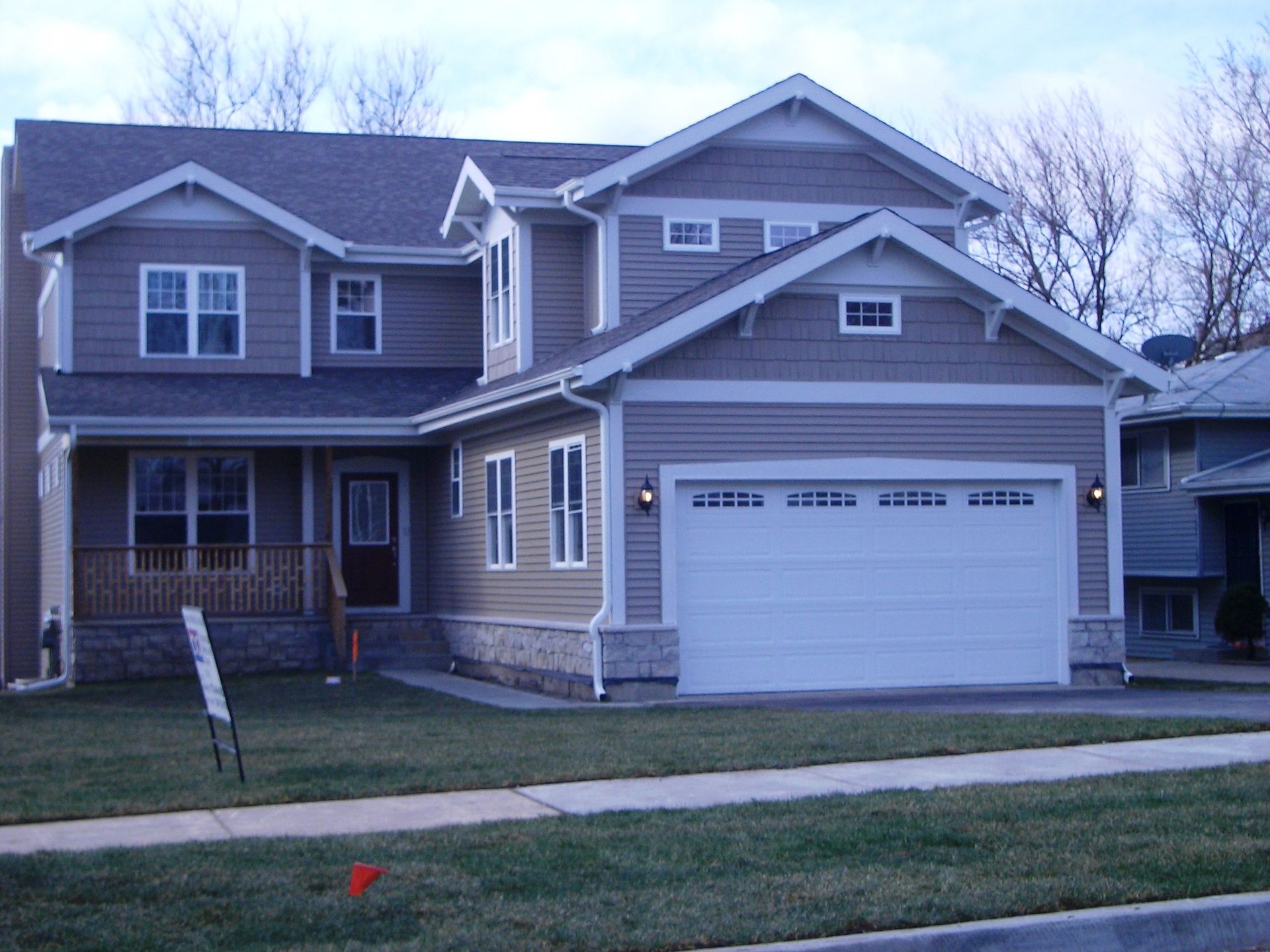 A large house with a white garage door is for sale