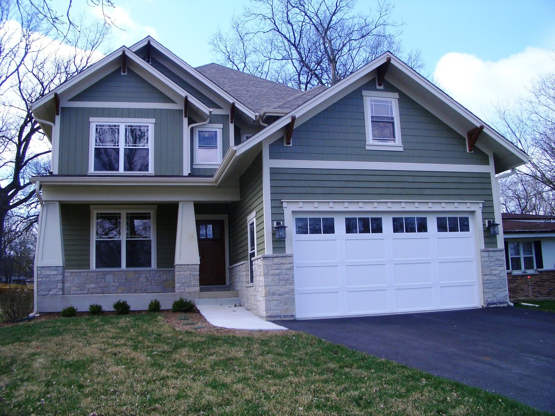 A house with green siding and a white garage door