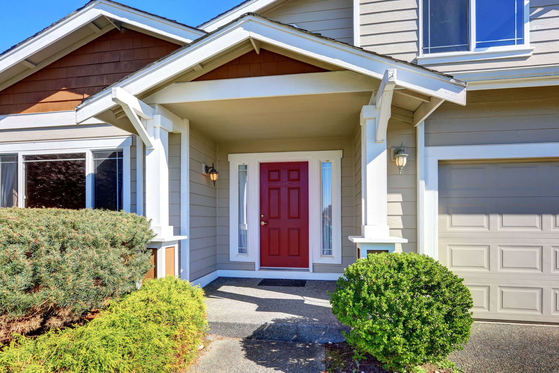 The front of a house with a red door and a porch.