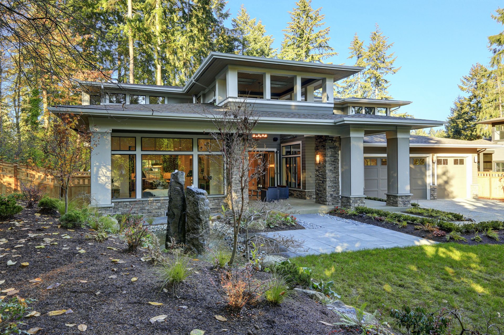 A modern house with a lot of windows is surrounded by trees.