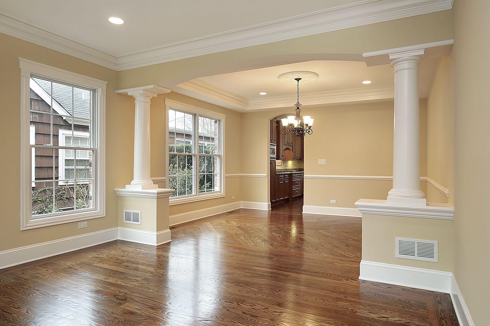 An empty living room with hardwood floors and columns.
