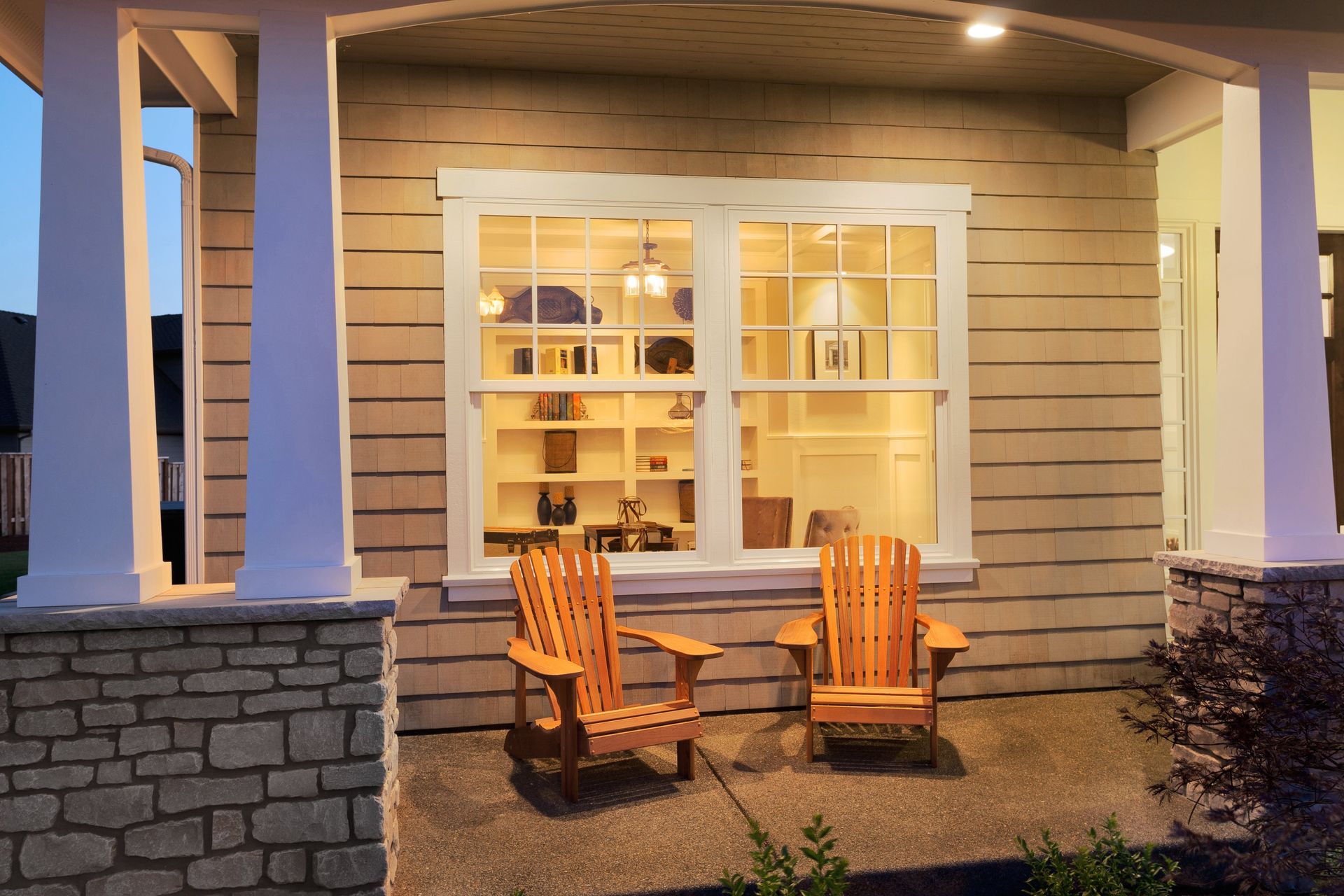 Two wooden chairs are sitting on the porch of a house.