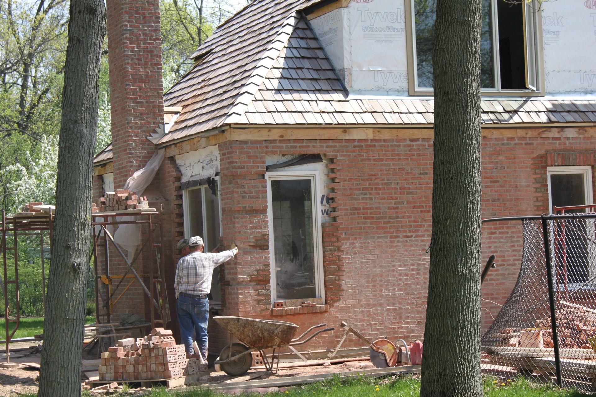 A man is standing in front of a brick house under construction
