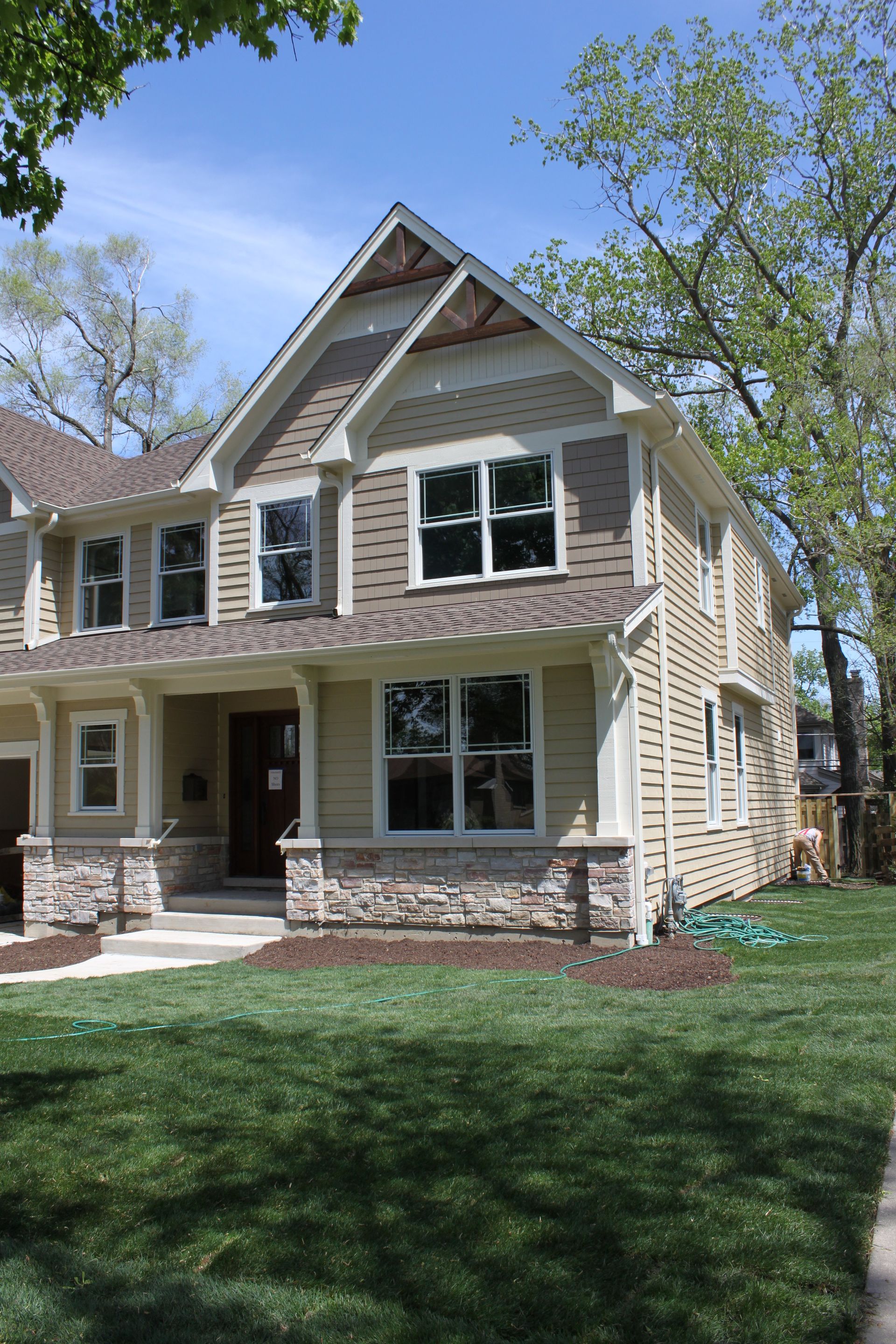 A large house with a lot of windows is sitting on top of a lush green lawn.
