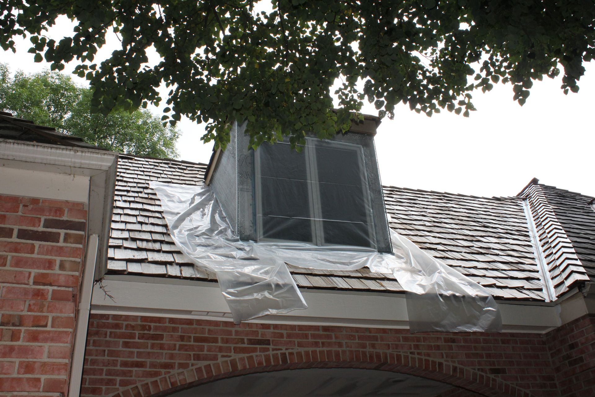 A brick building with a roof that is covered in plastic