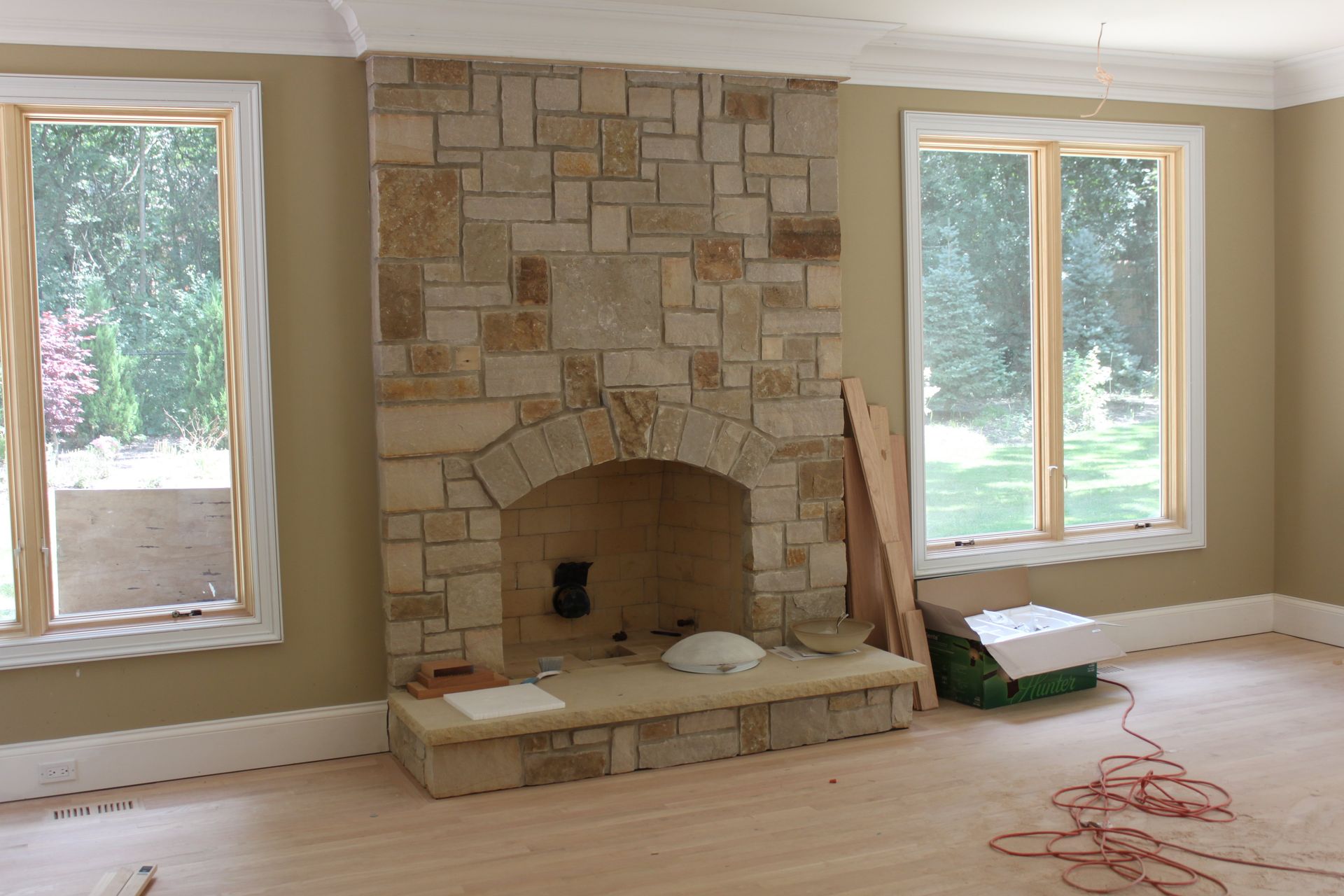 A living room with a stone fireplace and two windows