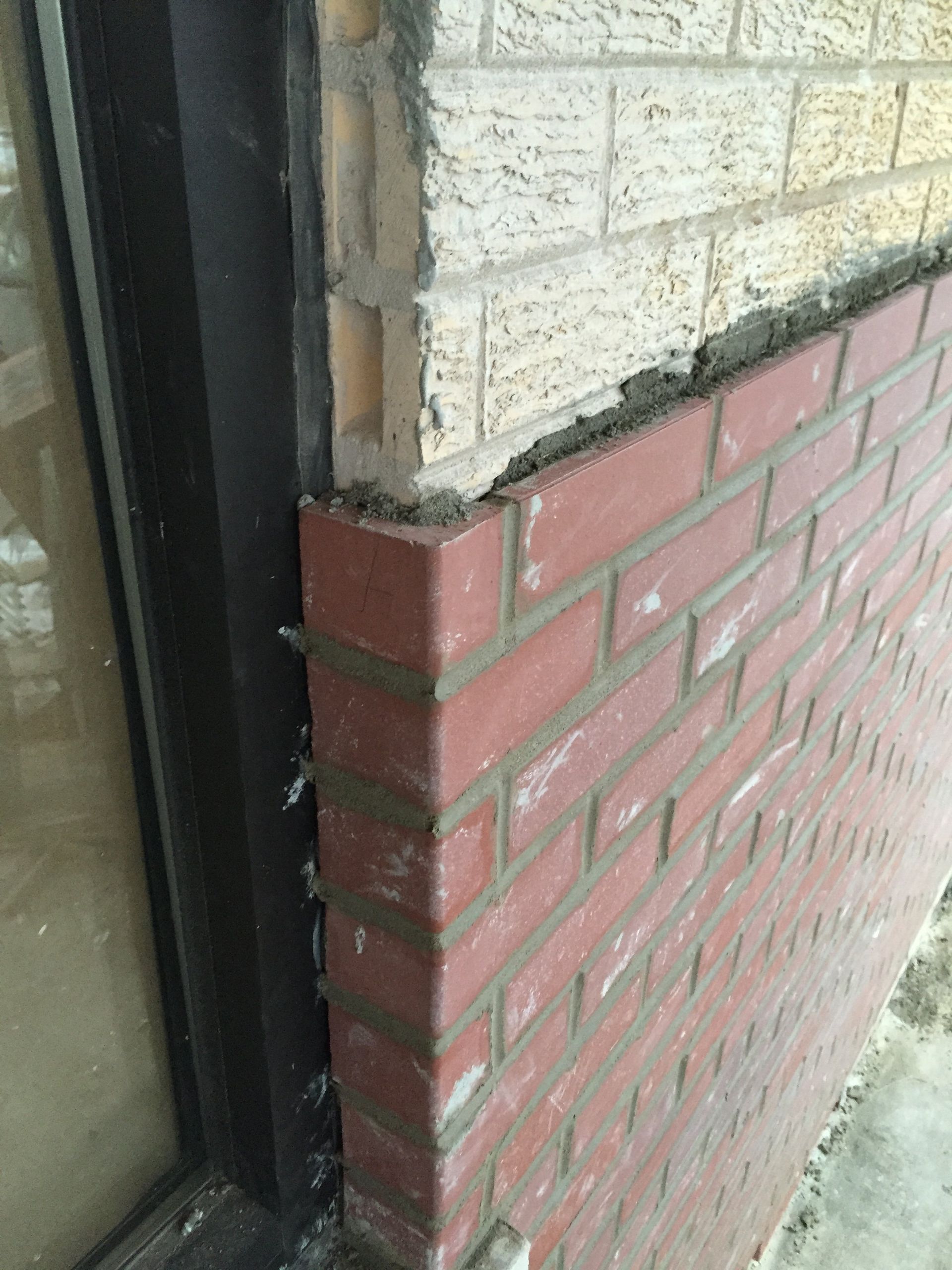 A close up of a brick wall next to a window.