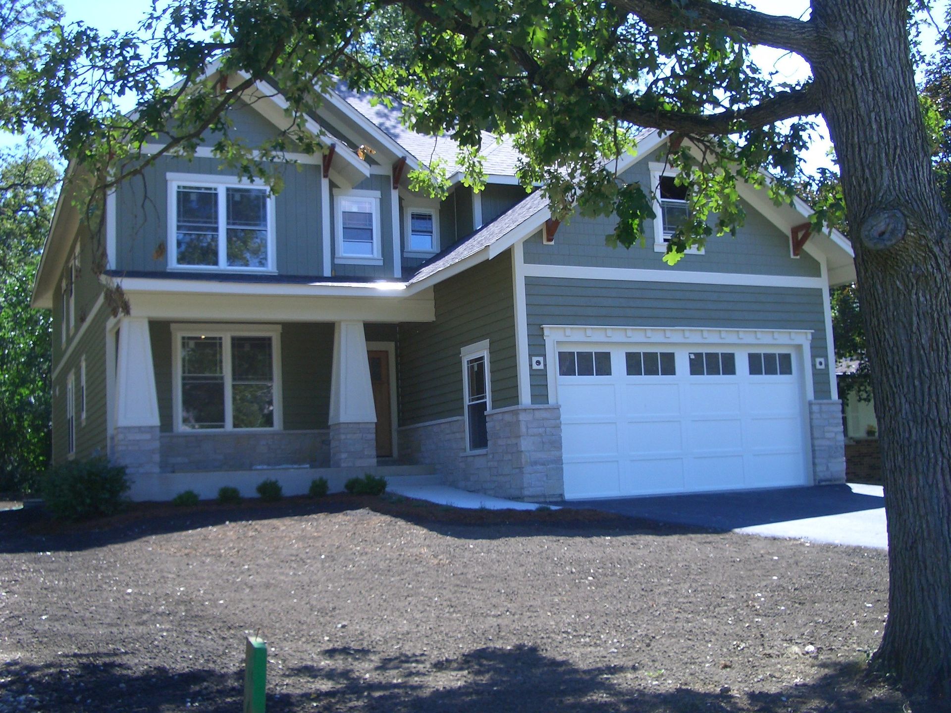 A house with a white garage door and a tree in front of it