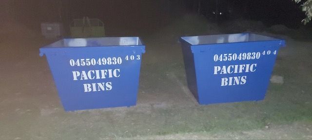Two blue pacific bins are sitting next to each other on a sidewalk.