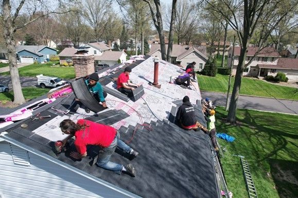 A group of people are working on the roof of a house.