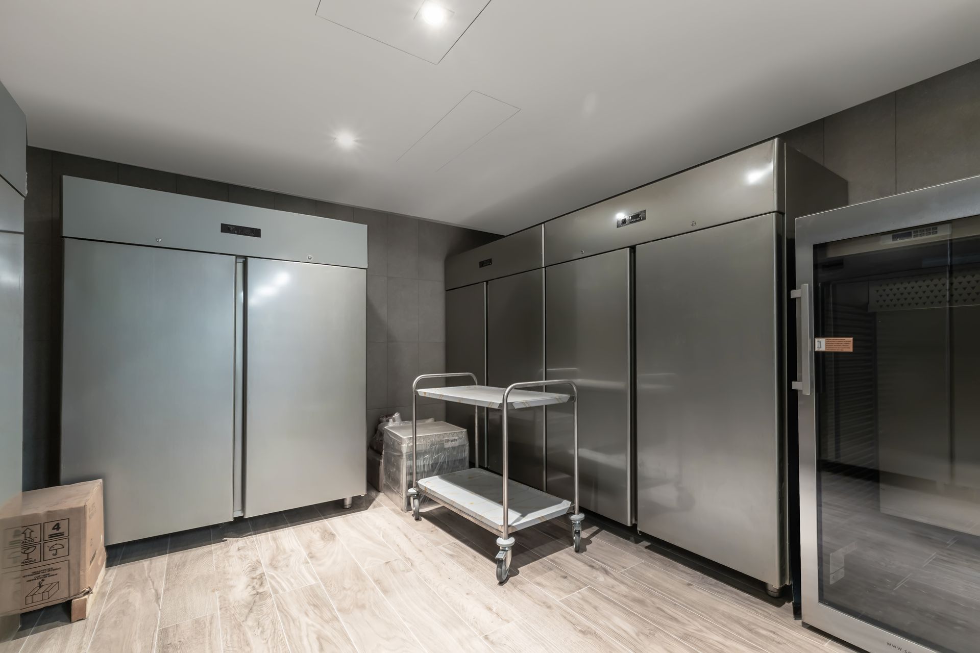 Modern stainless-steel hallway with double doors and a metal cart in a clean indoor facility