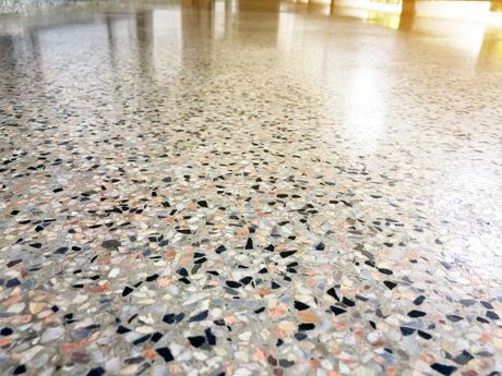 Close-up view of a polished terrazzo floor with a mottled pattern of black, gray, and tan aggregates.
