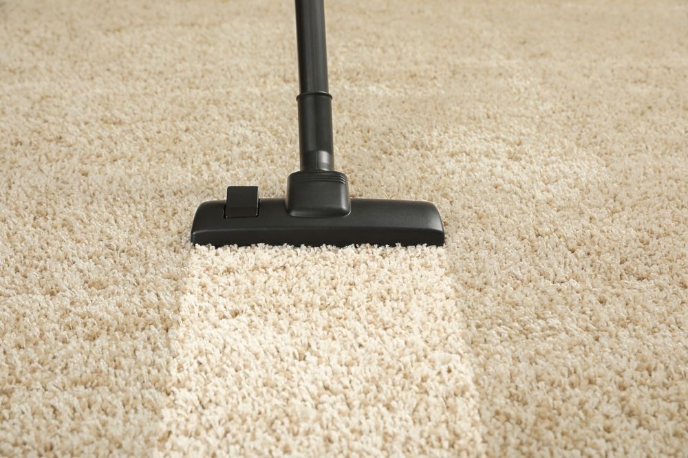 Vacuum cleaner cleaning a beige carpet, leaving a clean stripe.