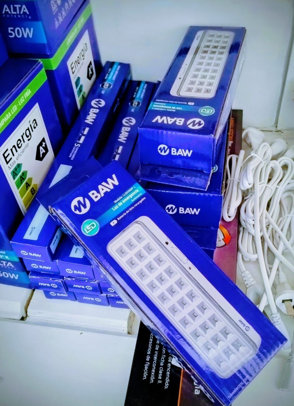 Cajas de luces LED azules y blancas apiladas con un cable de alimentación blanco a la vista.