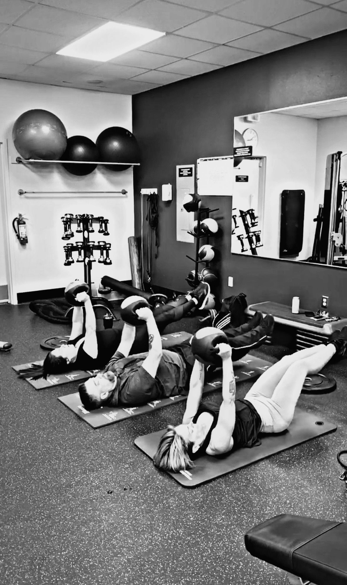 A group of people are doing exercises on yoga mats in a gym.