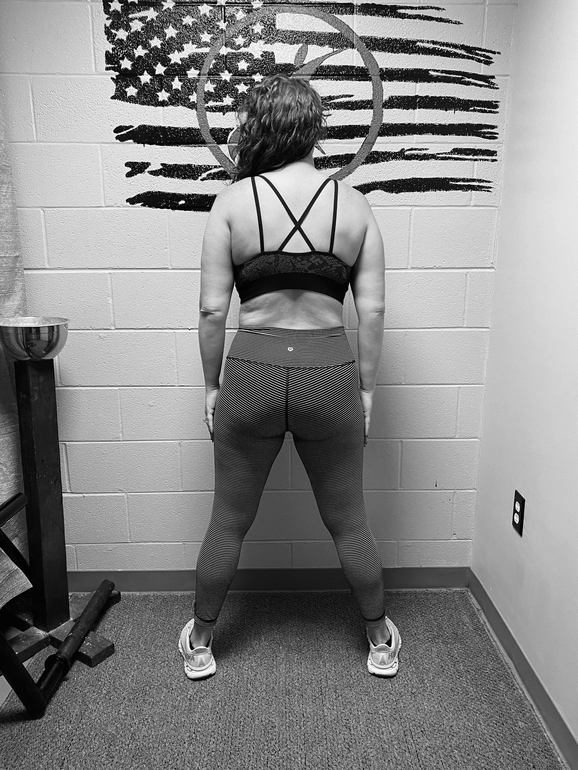 A woman is standing in front of an american flag in a gym.