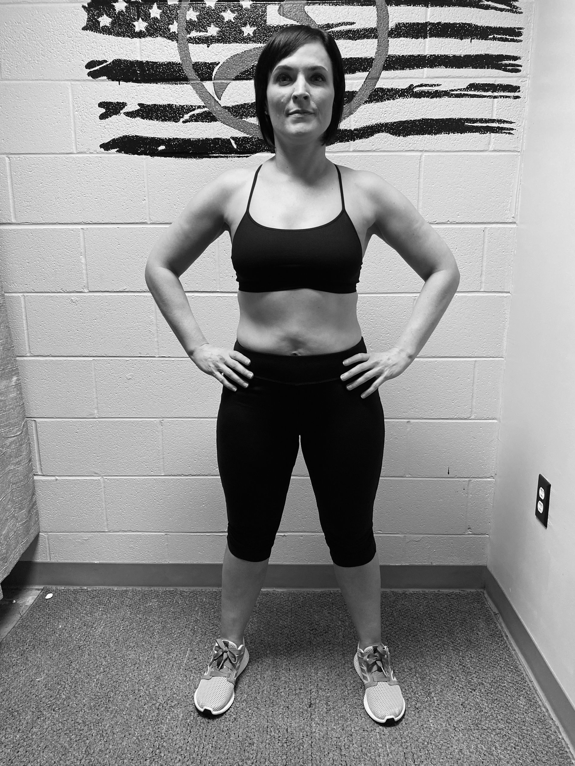 A woman standing in front of an american flag with her hands on her hips