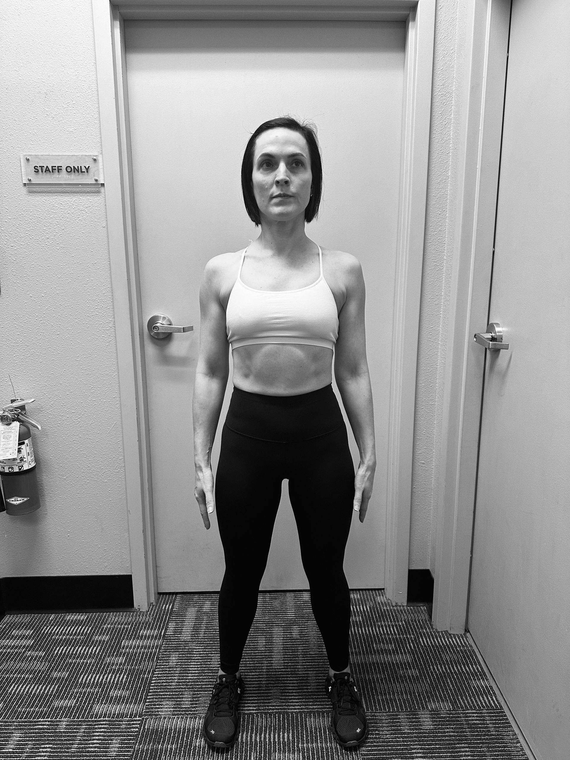 A woman is standing in front of a door in a black and white photo.