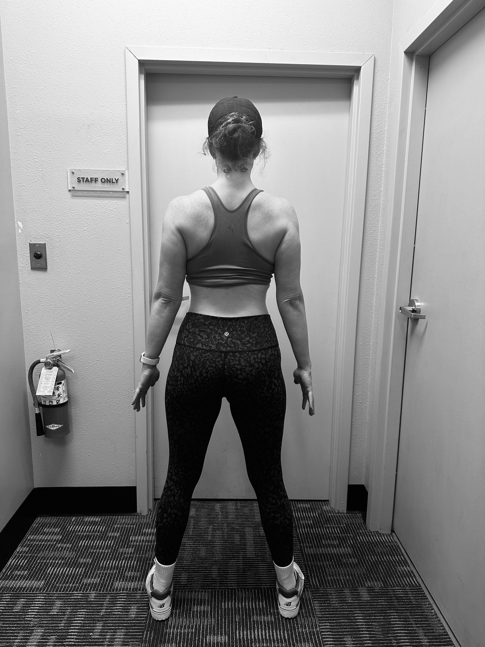 A woman is standing in front of a door in a hallway.
