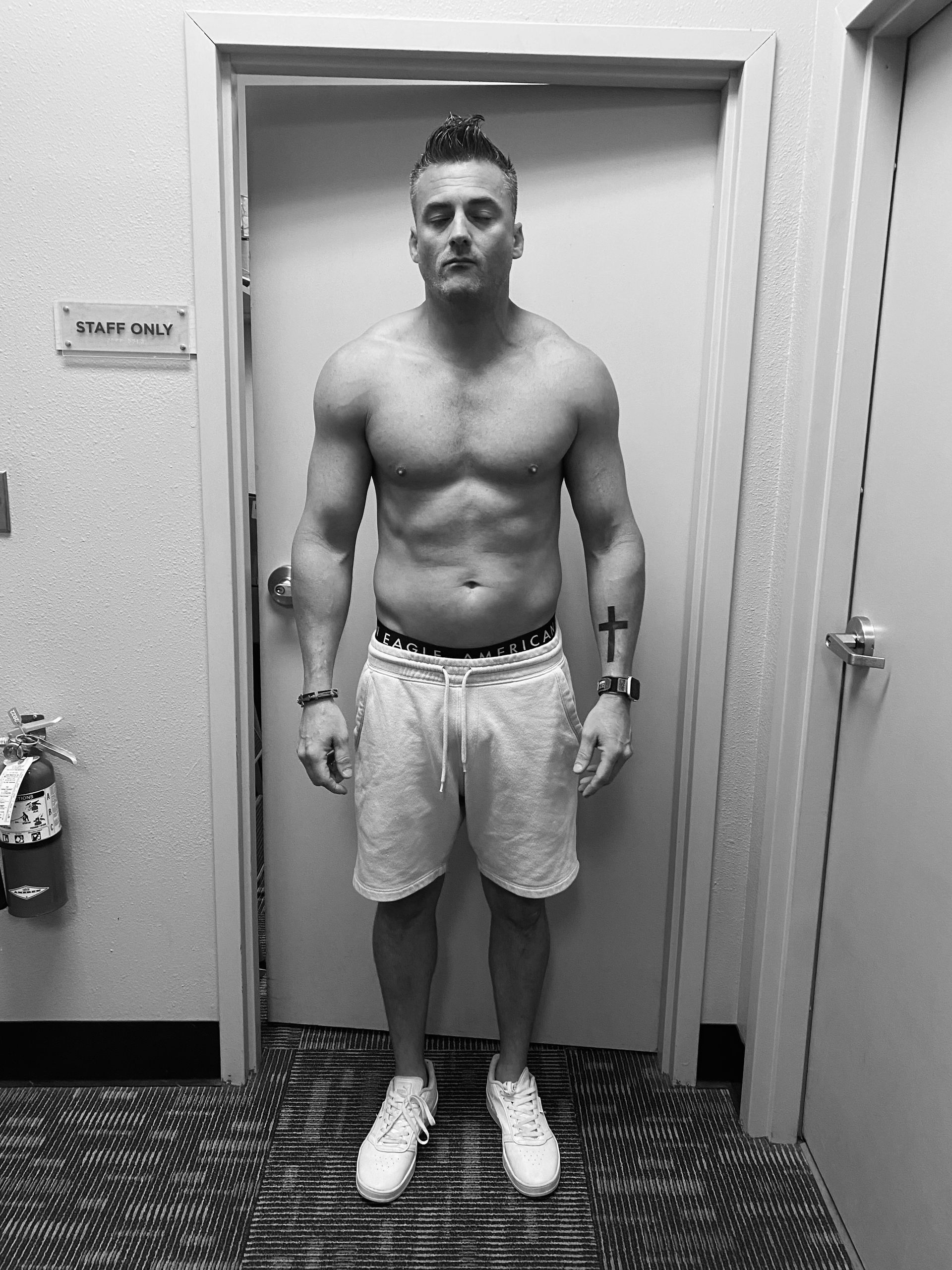A shirtless man is standing in front of a door that says staff only