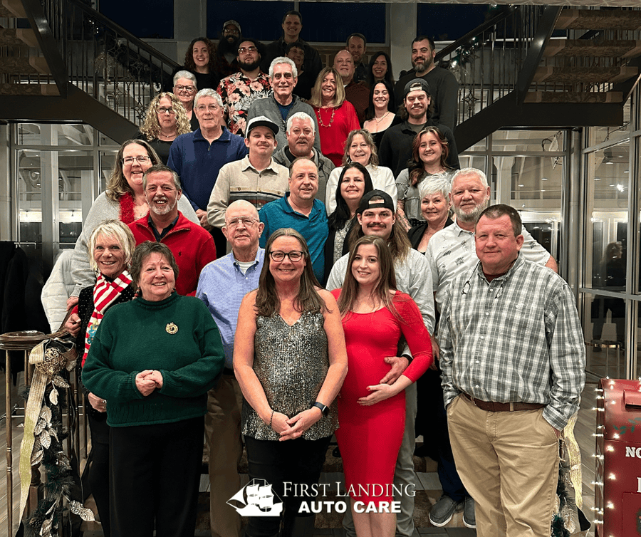 First Landing team posing on indoor stairs, with one person in a red dress front center and First Landing logo at bottom.