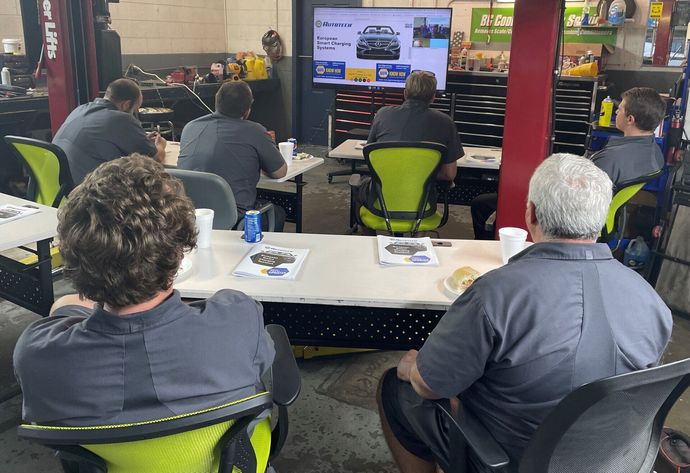 People seated at tables watching a TV presentation in an indoor event space