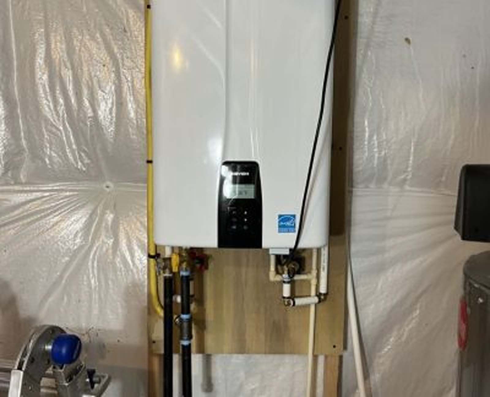 A white water heater is hanging on a wall in a room.
