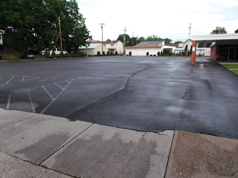 An empty parking lot with a few houses in the background