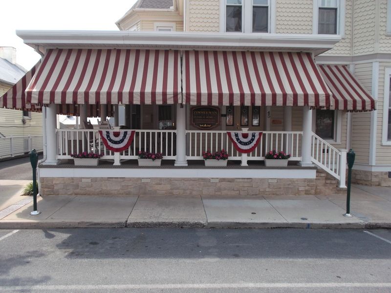 A house with a red and white striped awning on the porch