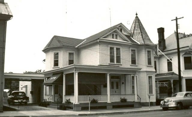 A black and white photo of a house with a porch