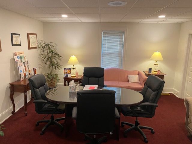 A conference room with a table and chairs and a pink couch