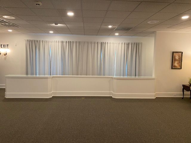 A large empty room with white curtains and a table.