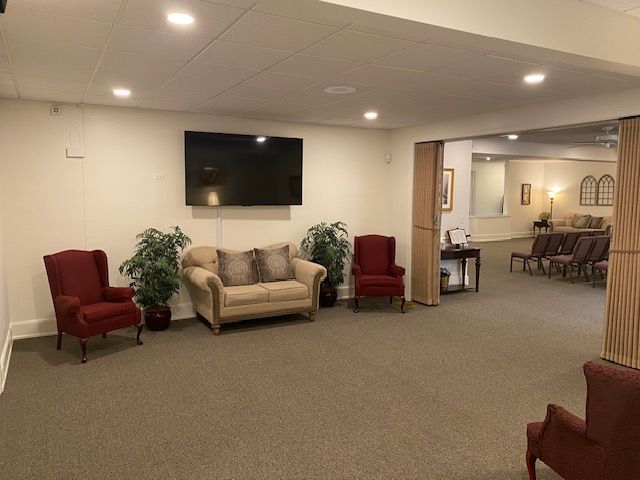 A living room with a couch , chairs and a flat screen tv.