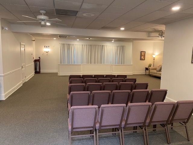 A room with rows of chairs in it and a ceiling fan.