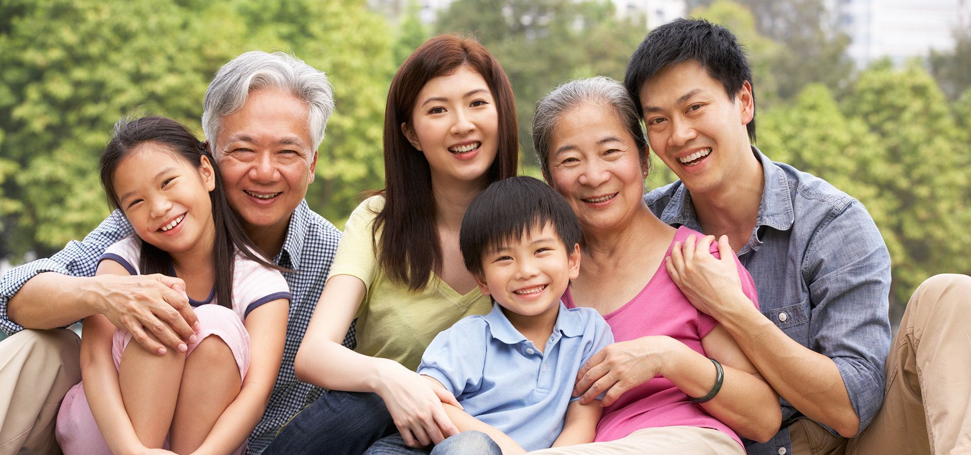 A family is posing for a picture while sitting on a blanket in the grass.